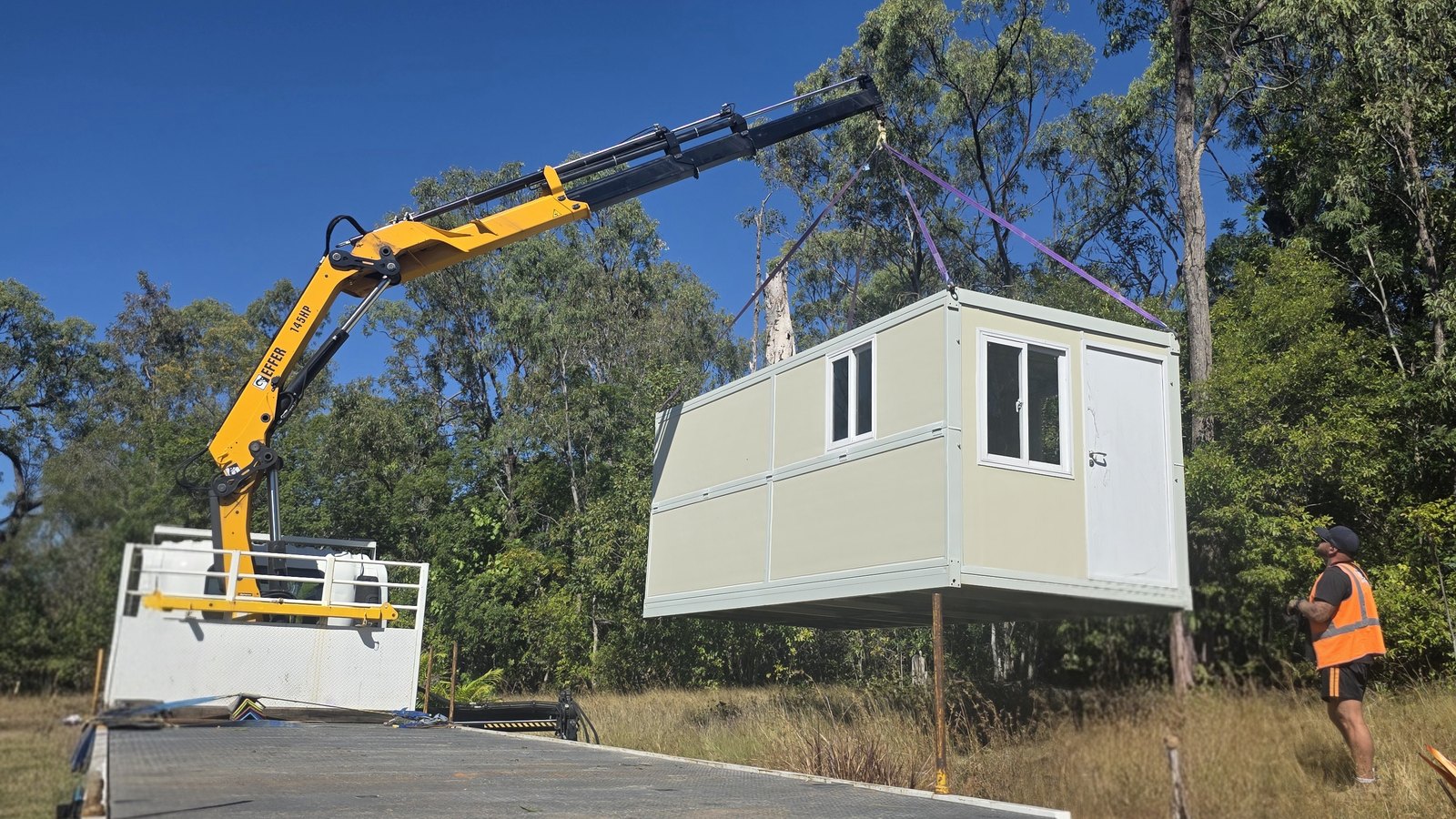 JMG Transport's 12-tonne front-mounted crane truck lifting a transportable building near Mackay