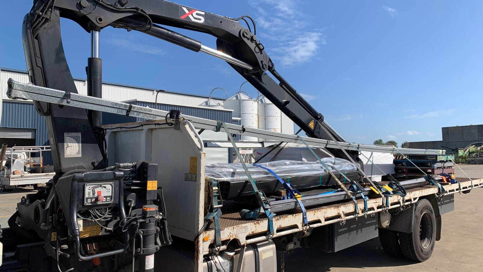 JMG Transport flatbed crane truck carrying bundled steel in a Mackay industrial yard